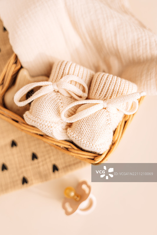 米色针织靴子放在一个装有婴儿配件的藤编篮子里图片素材
