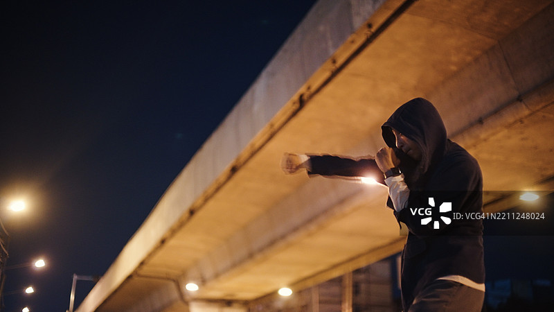 拳击手在夜晚的街道旁训练。图片素材