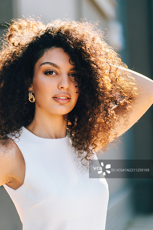 自信的多种族女性在户外，抚摸着自己的头发并看向镜头图片素材