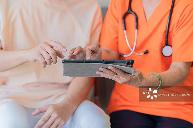 医生的手握着智能平板电脑，向患者展示恢复状态的特写照片图片素材