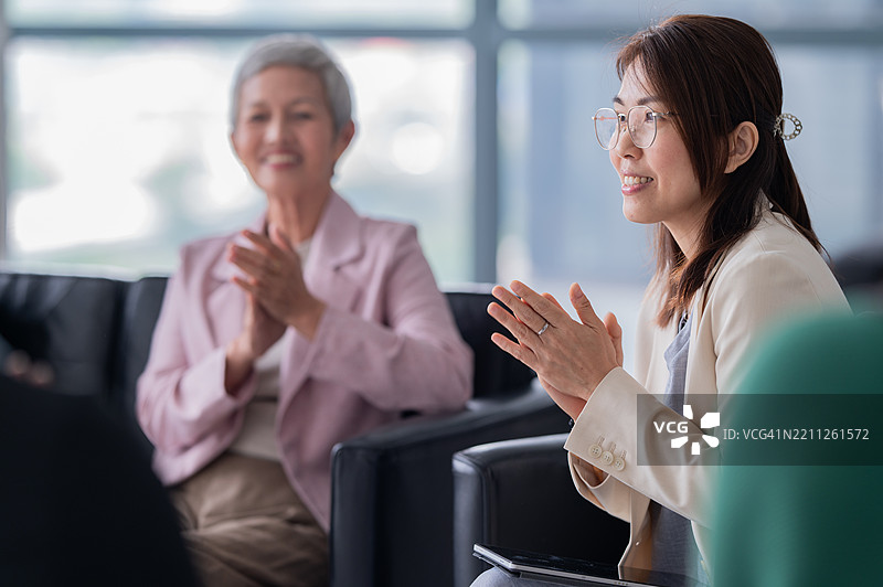 亚洲女商人在工作空间与同事进行讨论会议，大家鼓掌图片素材