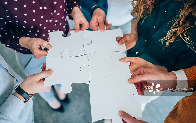一群商务人士手持拼图碎片。图片素材