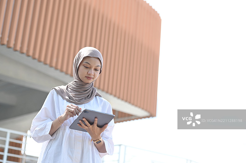 亚洲女性在户外使用平板电脑图片素材