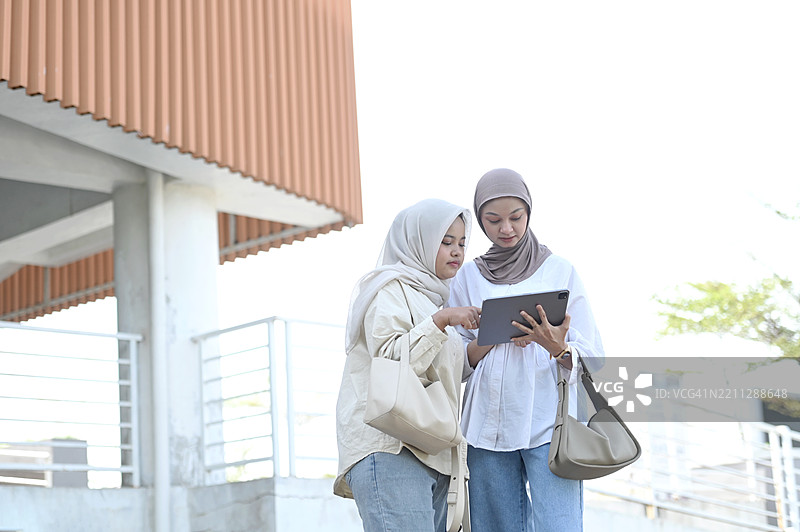 两位亚洲女性在户外使用平板电脑图片素材
