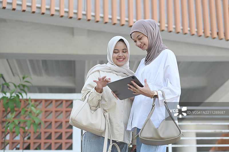 两位亚洲女性在户外使用平板电脑图片素材