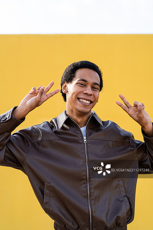 年轻男子用双手比出和平手势并微笑图片素材