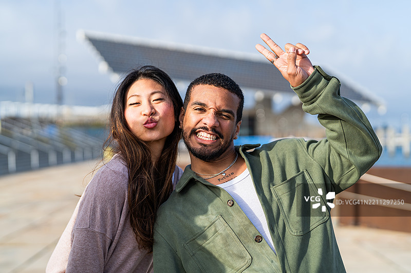 顽皮的年轻情侣做搞笑表情并比出和平手势图片素材