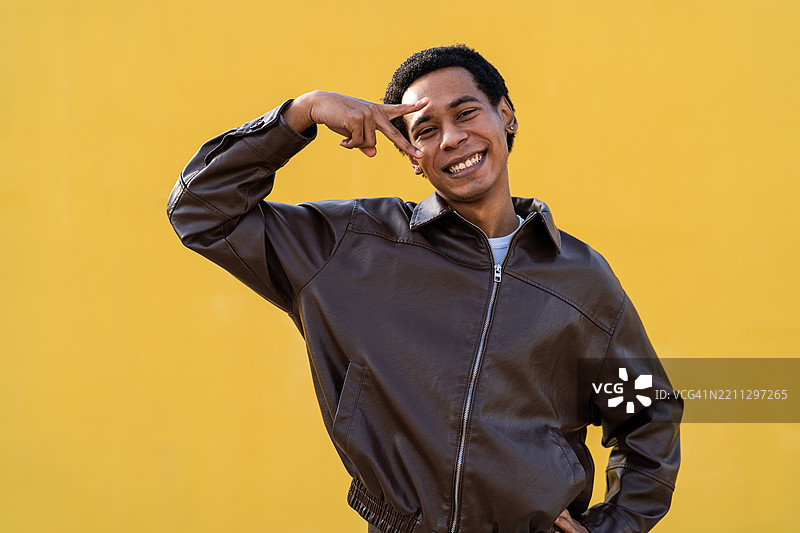 年轻男子用手指比出和平手势并对着镜头微笑图片素材