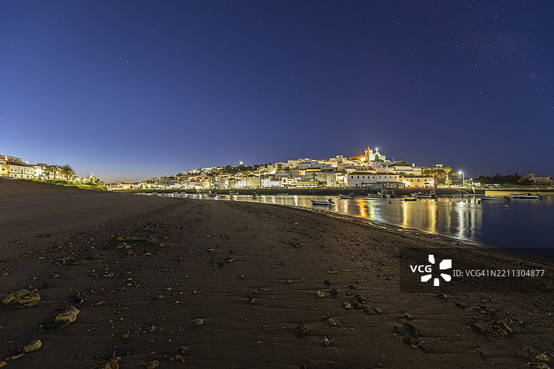 低潮时的沙滩和港口夜景。费拉古多,波尔蒂芒,阿尔加维,葡萄牙,欧洲的黎明时分,照亮的历史市中心全景图。图片素材