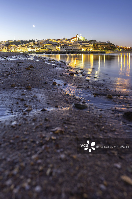 低潮时的沙滩和港口夜景。费拉古多,波尔蒂芒,阿尔加维,葡萄牙,欧洲的黎明时分,照亮的历史市中心全景。图片素材