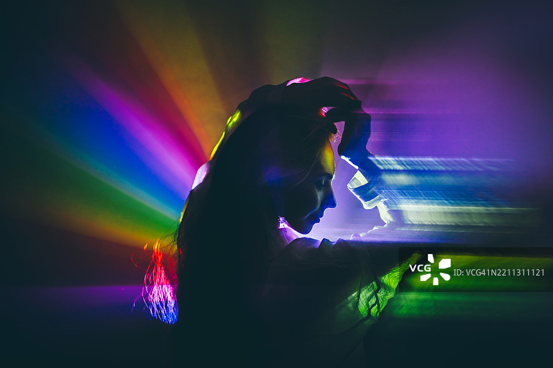 美丽女性的剪影在神奇的彩虹光芒和烟雾中。图片素材