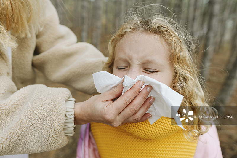 女人在森林里温柔地为女孩擦鼻子图片素材