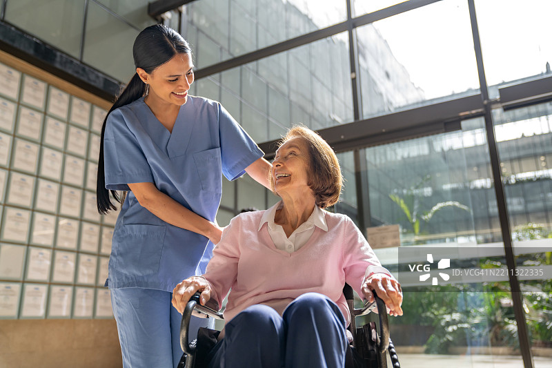 护士在医院推着一位老年女性坐在轮椅上图片素材