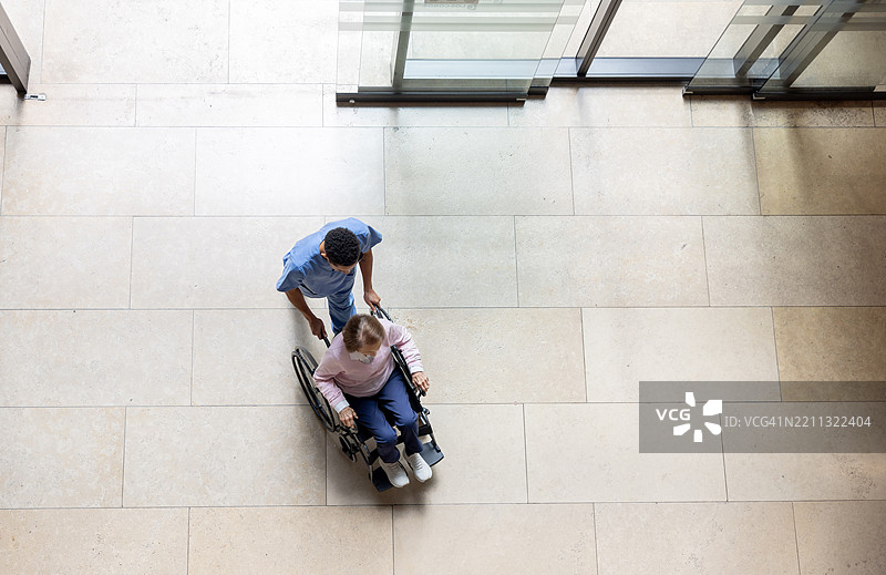 护士在医院推着一位老年女性坐在轮椅上图片素材