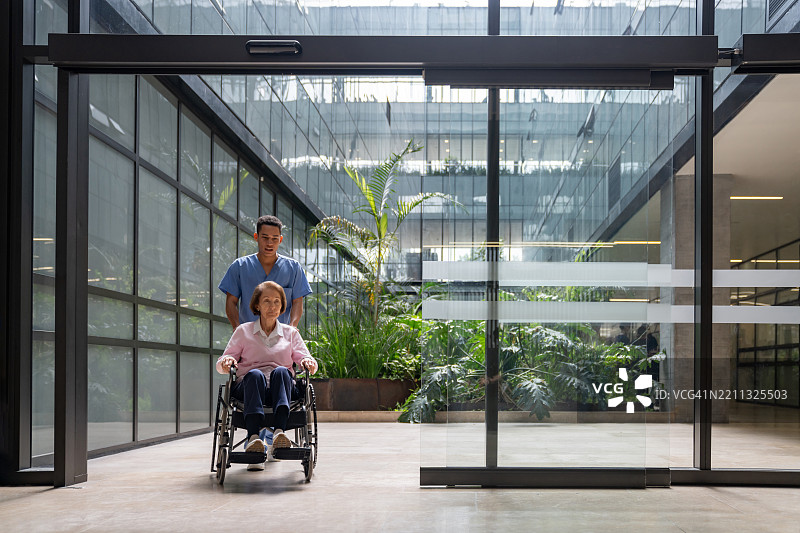 护士在医院推着一位老年女性坐在轮椅上图片素材