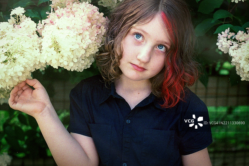 盛开的绣球花映衬着五彩斑斓的头发。胶卷摄影捕捉了春花中的青春。图片素材