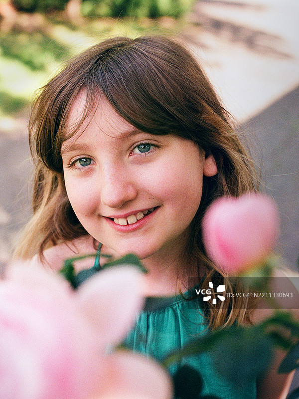 花丛中的快乐表情。绿眼睛的中长发少年在胶卷照片中。图片素材