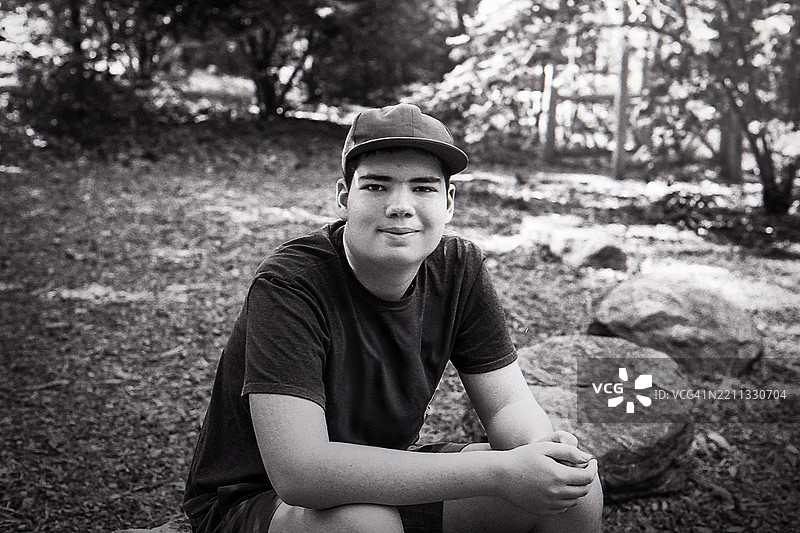 青少年在树林公园放松。年轻人坐在岩石上，享受户外的下午时光。图片素材