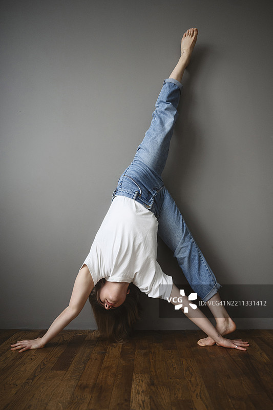 年轻女性在墙边拉伸和练习舞蹈特技图片素材