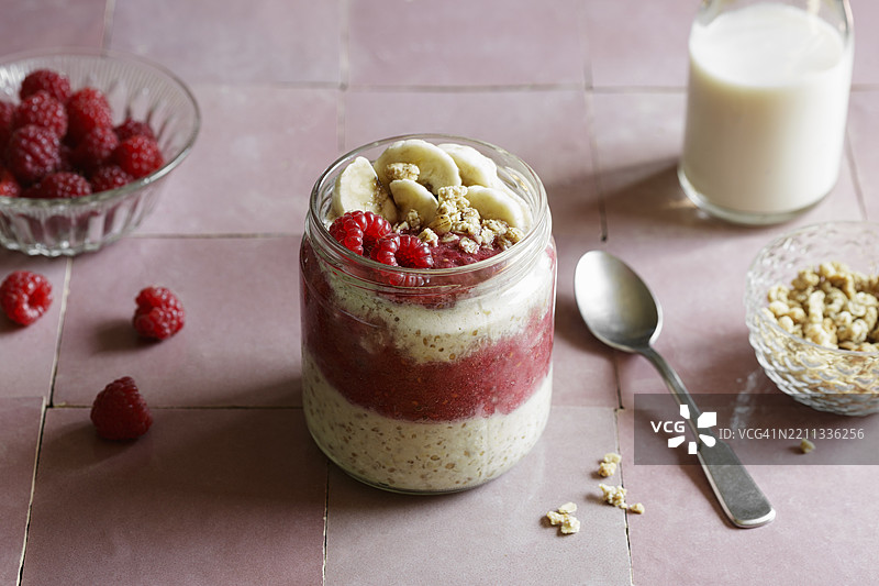素食者的覆盆子香蕉隔夜燕麦，装在玻璃罐中，配有燕麦奶，背景为工作室环境图片素材