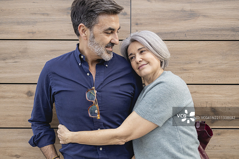 幸福的情侣在木质背景前拥抱图片素材