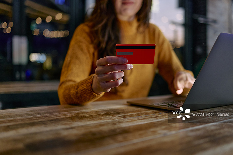 女性在室内使用信用卡和笔记本电脑进行网上购物图片素材
