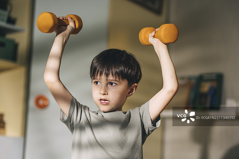 孩子在室内举哑铃，倡导健康生活方式图片素材