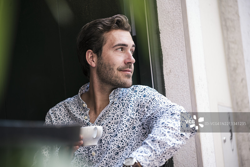 年轻男子在室内享受咖啡，神情沉思图片素材