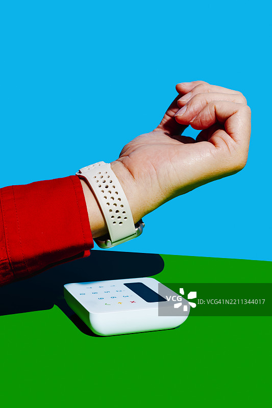 男子在色彩缤纷的工作室环境中使用智能手表通过支付终端付款图片素材