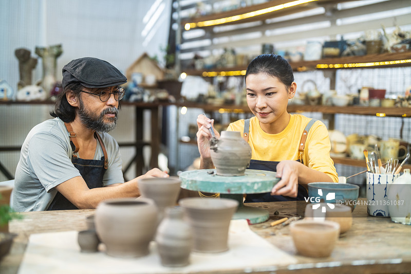 教师与学生一起进行陶艺课程，制作装饰性陶土容器图片素材