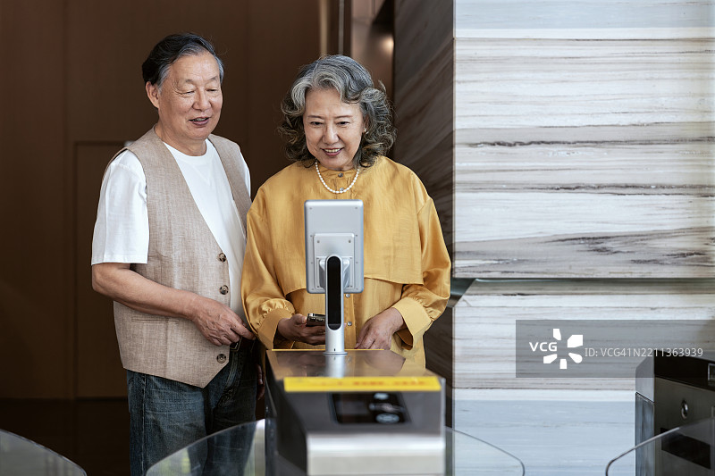 亚洲高级商务人士使用面部识别技术打开办公大楼的门。图片素材