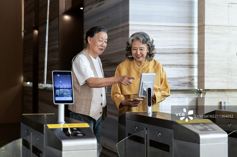 亚洲高级商务人士使用面部识别技术打开办公大楼的门。图片素材