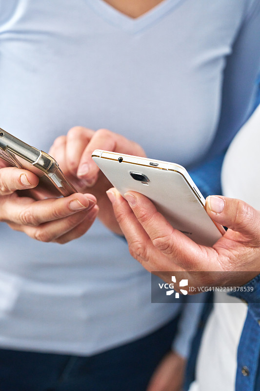 两个朋友互动并通过智能手机享受乐趣图片素材