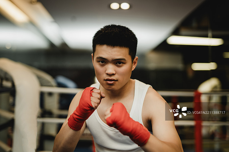 年轻的亚洲拳击手在拳击台上看着镜头图片素材