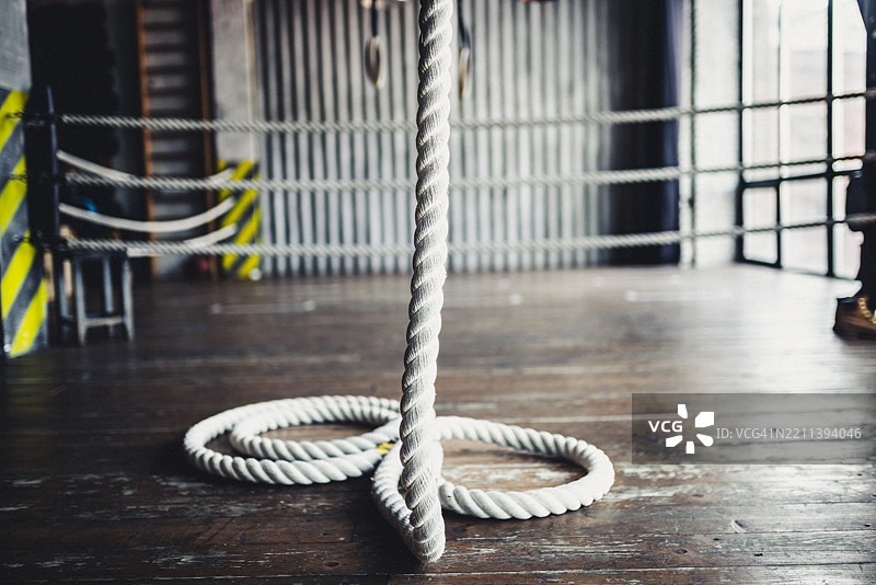 自然光下的木质健身房地板上盘绕的运动绳图片素材
