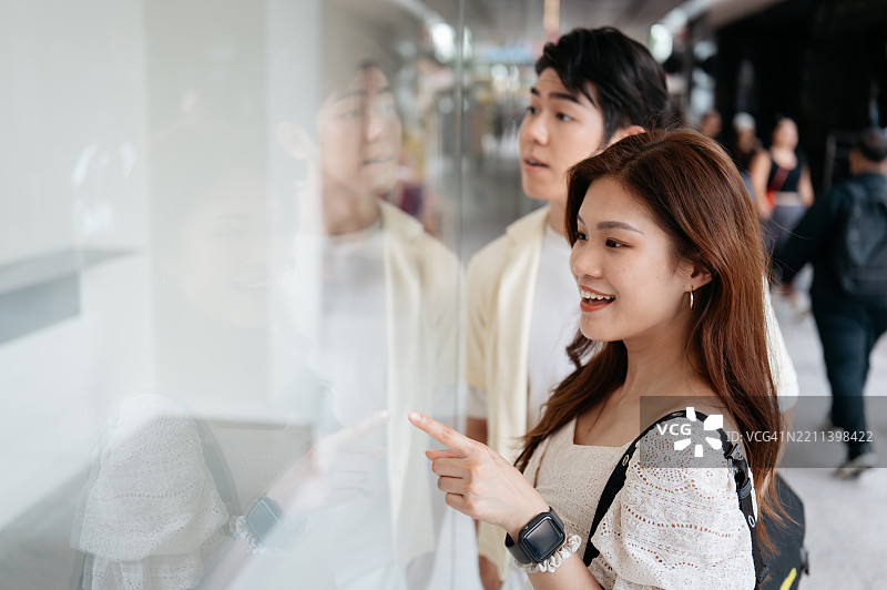 亚洲情侣在百货商场橱窗购物图片素材