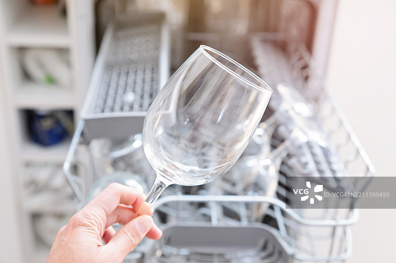 手握酒杯站在洗碗机前图片素材