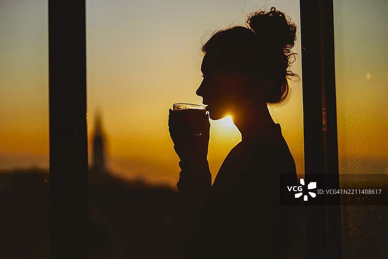 年轻女士在日落时分喝咖啡的剪影系列图片素材