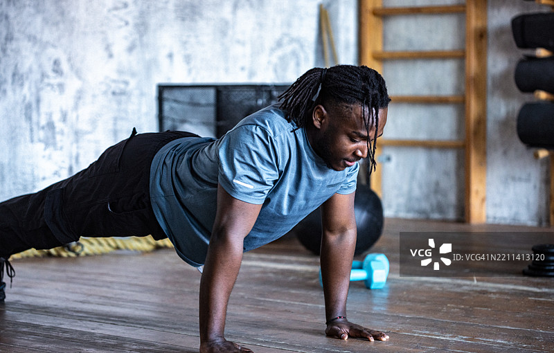 男子在健身房环境中进行俯卧撑锻炼图片素材
