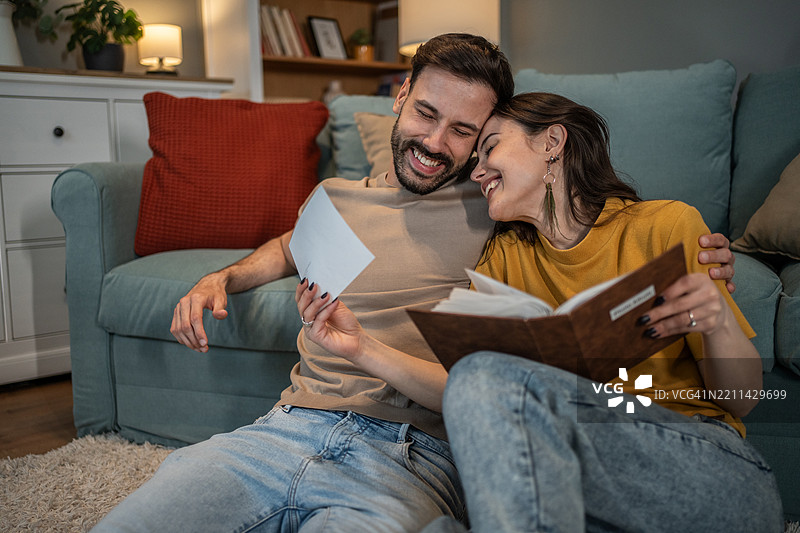 快乐的情侣在家中微笑着翻看相册，分享美好回忆图片素材