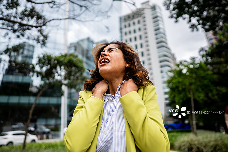 年轻女商人在街上感到肩部疼痛图片素材