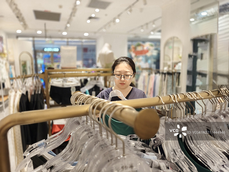 女人仔细挑选她喜欢的衣服图片素材
