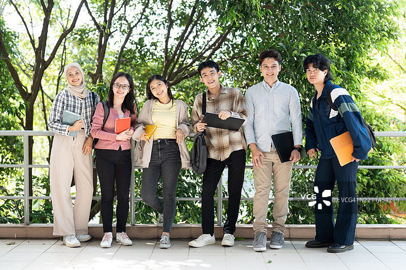 快乐的多民族同学们在大学校园里看着镜头站着图片素材