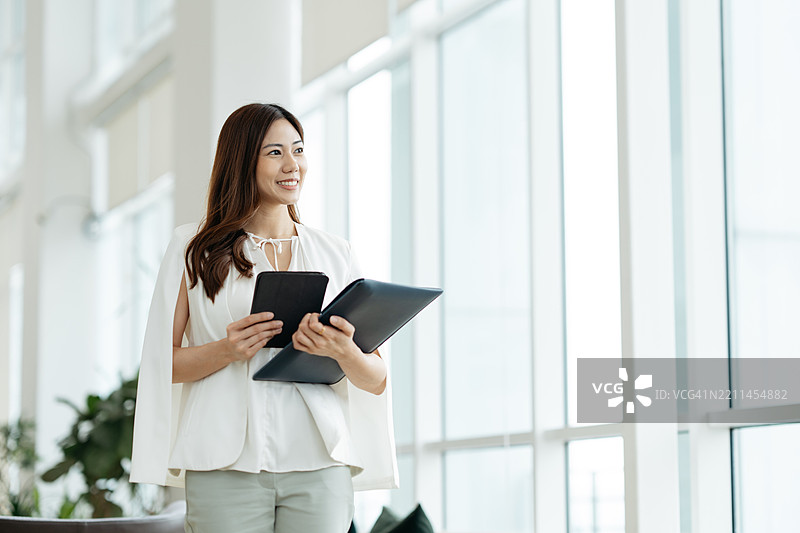 自信的女性企业家在现代办公室使用平板电脑和笔记本电脑图片素材