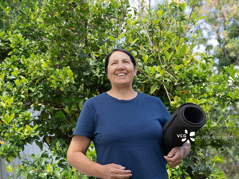 微笑的成熟的女性在公园里拿着瑜伽垫图片素材