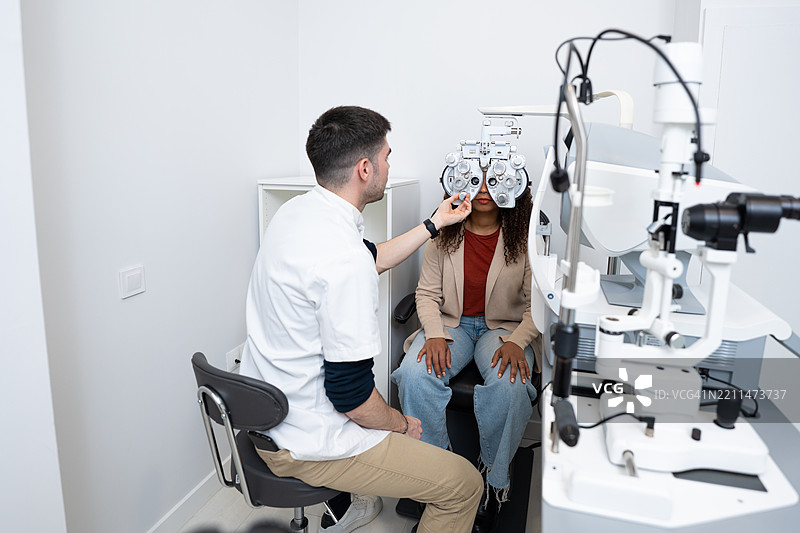 验光师在眼科诊所使用验光仪检查患者视力图片素材