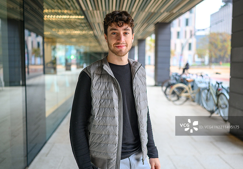 年轻男子在城市环境中微笑，穿着背心图片素材