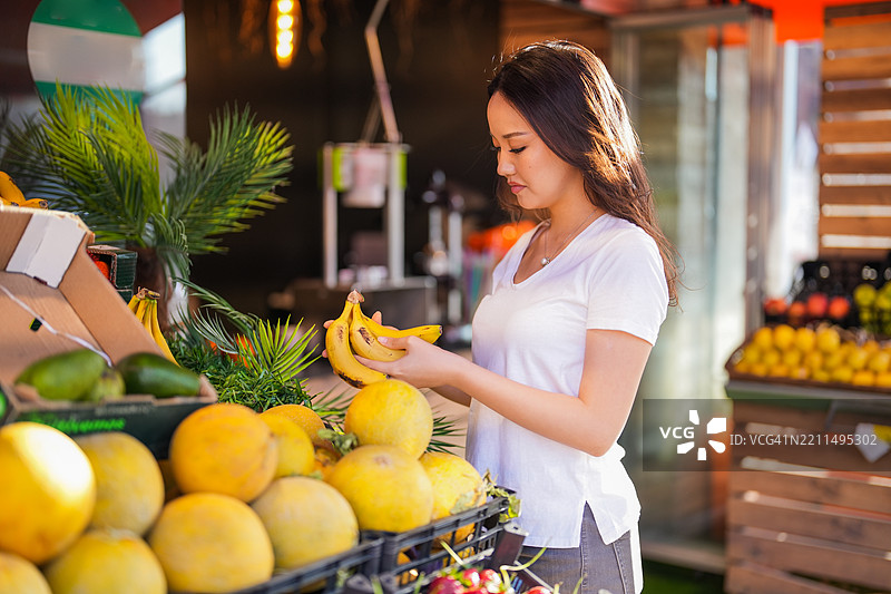 年轻的亚洲女性在农贸市场挑选水果和蔬菜图片素材