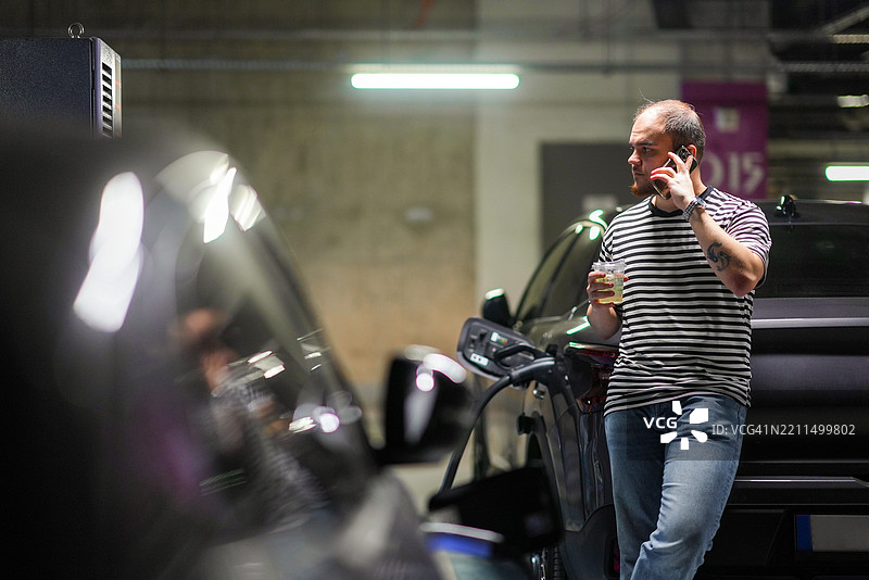 电动车充电站，男子为他的汽车充电，使用二维码进行移动支付，下一代车辆图片素材