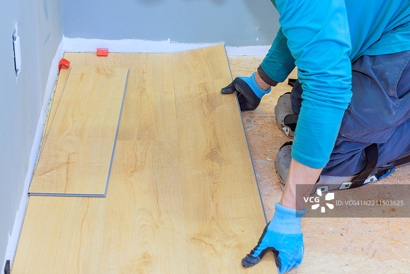 工人在灰色墙壁的房间里安装复合地板图片素材